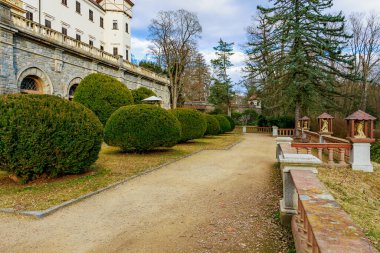 Sakin park ortamında manikürlü bahçe yolu olan tarihi taş köşk. 17 Mart 2025, Konopiste Şatosu, Çek Cumhuriyeti.