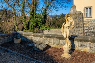Güneşli bir günde tarihi bahçedeki zarif taş kadın heykeli. 16 Mart 2025, Hruba Skala Şatosu, Çek Cumhuriyeti.