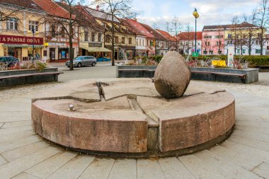 Şehir meydanında tarihi binaları olan yuvarlak taş heykel. 17 Mart 2025, Benesov, Çek Cumhuriyeti.