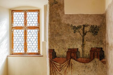 Güneşli odada antik duvar resmi olan tarihi bir pencere. 18 Mart 2025, Madalyon, Çek Cumhuriyeti.