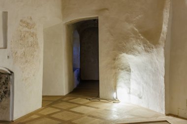 Tarihi bir binada ahşap zemini ve yumuşak ışıklandırması olan antik taş koridor. 18 Mart 2025, Madalyon, Çek Cumhuriyeti.