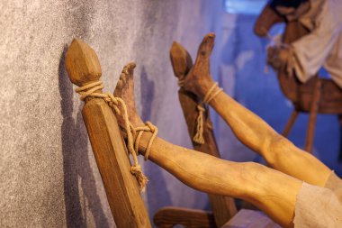 Ortaçağ işkence sahnesinde ahşap kayışlar ve sıkıntılı figürlerle askı tasvir ediliyor. 18 Mart 2025, Madalyon, Çek Cumhuriyeti.