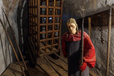 Maskeli figür ve işkence aletleriyle ortaçağ zindan sahnesi. 18 Mart 2025, Madalyon, Çek Cumhuriyeti.