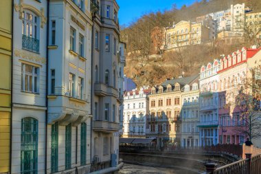 Karlovy nehri boyunca uzanan renkli tarihi binalar çeşitlilik gösteriyor, Çek Cumhuriyeti. 18 Mart 2025, Karlovy Vary, Çek Cumhuriyeti.