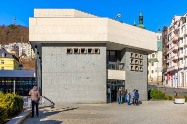 Şehir manzarasında turistlerin olduğu modern gri taş bina. 18 Mart 2025, Karlovy Vary, Çek Cumhuriyeti.