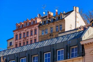 Renkli yüzler ve çatı antenleri ile aydınlık bir günde tarihi mimari. 19 Mart 2025, Karlovy Vary, Çek Cumhuriyeti.