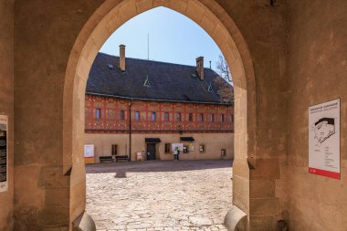 Mavi gökyüzünün altında avlu manzaralı tarihi kale girişi. 19 Mart 2025, Karlstejn, Çek Cumhuriyeti.