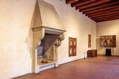 Ahşap tavanı ve sergilenen sanat eserleri olan tarihi taş şömine. 19 Mart 2025, Karlstejn, Çek Cumhuriyeti.