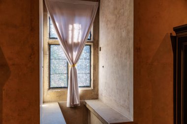 Kır taşından bir köşede perdesi olan rahat bir güneş ışığı köşesi. 19 Mart 2025, Karlstejn, Çek Cumhuriyeti.