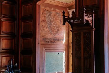 Tarihi odada karmaşık ahşap işçiliği ve kraliyet sembolü. 19 Mart 2025, Karlstejn, Çek Cumhuriyeti.