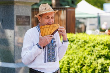 Kültürel kıyafetlerle geleneksel pan flütü çalan yaşlı beyaz bir erkek. 22 Mayıs 2025 Balti Moldova.