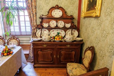 Süslü ahşap dolap ve porselen tabaklar ile Viktorya dönemi yemek odası sergisi. 20 Mart 2025, Cesky Krumlov, Çek.