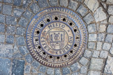 Çelimsiz Krumlov yazısıyla kaplı dairesel rögar kapağı. 20 Mart 2025, Cesky Krumlov, Çek.