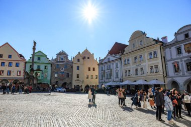Renkli mimari ve turistlerle dolu tarihi kasaba meydanında güneşli bir gün. 20 Mart 2025, Cesky Krumlov, Çek.