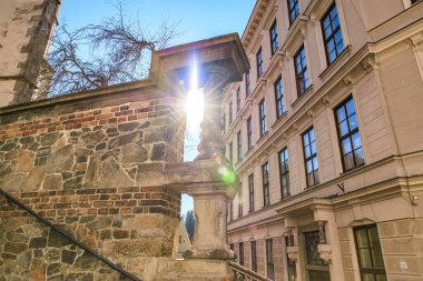 Şehir ortamında tarihi mimarisi olan taştan yapıların içinden güneş ışığı akıyor. 20 Mart 2025, Cesky Krumlov, Çek.