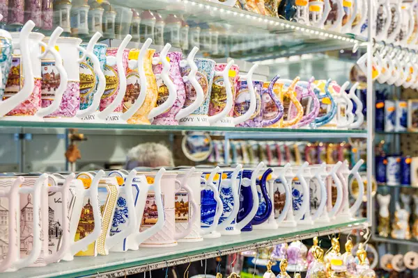 Hediyelik eşya dükkanının cam raflarında sergilenen renkli kupalar. 18 Mart 2025, Karlovy Vary, Çek Cumhuriyeti.