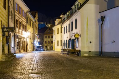 Aydınlanmış Avrupa kaldırım taşı sokağının tarihi binalarla dolu olduğu sessiz bir gece manzarası. 20 Mart 2025, Cesky Krumlov, Çek.