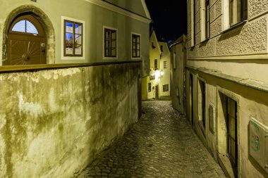 Tarihi Avrupa kasabasında geceleyin dar kaldırım taşlı dar bir sokak. 20 Mart 2025, Cesky Krumlov, Çek.