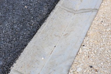 Beton kaldırım ve çakıl yüzeyi olan asfalt yol.