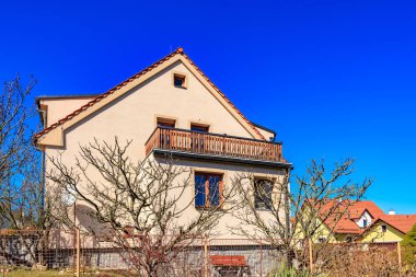 Açık mavi gökyüzüne karşı balkonlu banliyö evi.