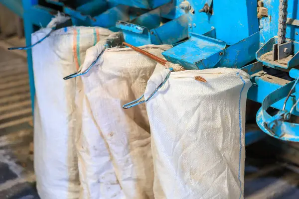 Mavi bir makineden sarkan üç torba beyaz madde.