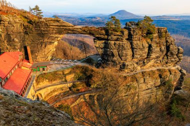 Manzaralı dağ manzarasında kırmızı çatılı görkemli doğal kaya köprüsü..