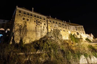 Geceleyin gökyüzüne karşı aydınlatılmış Cesky Krumlov şatosunun tarihi gece görüntüsü.
