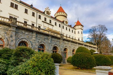 Taş mimarisi ve bulutlu gökyüzü altında kırmızı çatıları olan tarihi Avrupa kalesi.