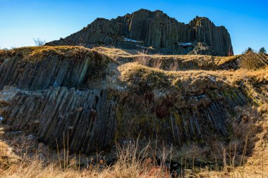 Engebeli dağ manzarasında görkemli altıgen bazalt sütunlar.