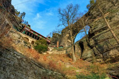 Resimli dağ pansiyonu, berrak mavi gökyüzü ile doğal kaya kemerinin altında..
