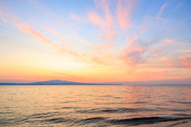 Gökyüzü güzel turuncu bir renktir ve su sakindir. Güneş batıyor ve bulutlar gökyüzünde
