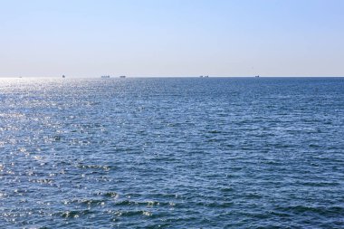 Sakin okyanus ufku, açık mavi gökyüzü altında uzak gemiler..