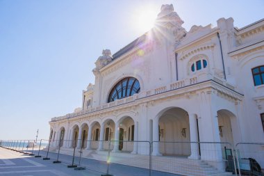 Güneş ışığında kemerli pencereleri olan tarihi beyaz bina.