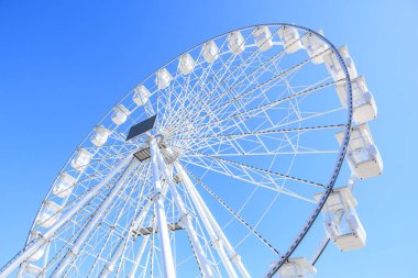 Güneşli bir günde açık mavi gökyüzüne karşı dev dönme dolap..