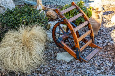 Bahçedeki tahta el arabası kuru çimenler ve kil çömlek ile.