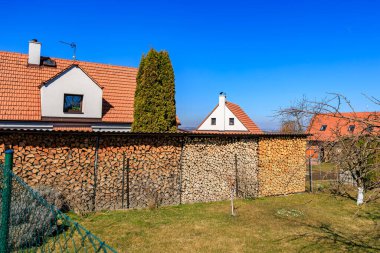 Kırsal kesimde yakacak odun yığınları ve açık mavi gökyüzü olan bir ev..