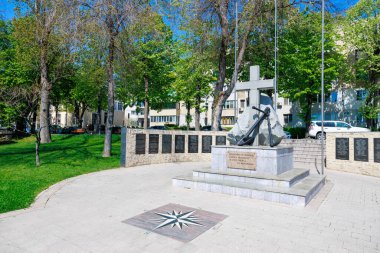 Çapa ve haç ağaçlar ve anıt plaklarıyla çevrili parkta. 3 Mayıs 2025 Romanya.