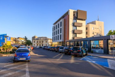 Gündüz vakti arabaları ve modern mimarisi olan modern şehir caddesi. 3 Mayıs 2025 Romanya.