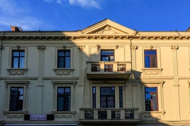 Mavi gökyüzü altında balkonu ve gölgesi olan tarihi Avrupa mimarisi. 3 Mayıs 2025 Romanya.