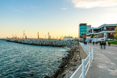 Gün batımında rıhtım manzaralı bir gezinti. Limanda insanlar geziniyor. 3 Mayıs 2025 Romanya.