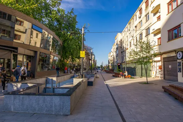 Güneşli bir günde modern mimari ve yaya geçidi olan şehir caddesi manzarası. 3 Mayıs 2025 Romanya.