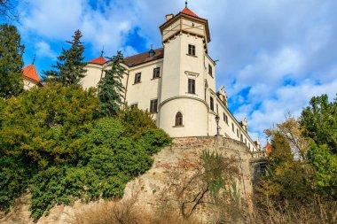 Mavi gökyüzünün altında kulesi olan ve yemyeşil yemyeşil olan tarihi Avrupa kalesi. 17 Mart 2025, Konopiste Şatosu, Çek Cumhuriyeti.