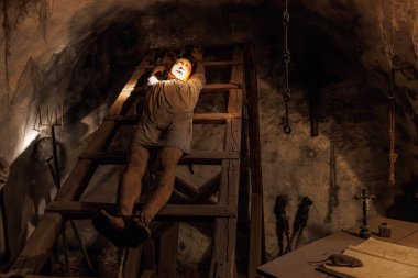 Ortaçağ zindan sahnesinde ahşap işkence sehpasında bir adam. 18 Mart 2025, Madalyon, Çek Cumhuriyeti.