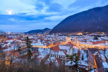 Geceleri ortasında büyük bir bina olan bir şehir. Gökyüzü bulutlu ve şehir aydınlık.
