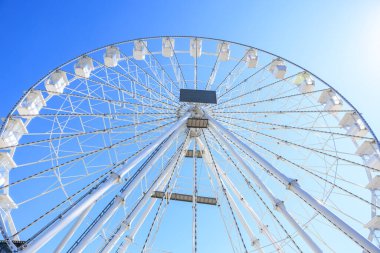 Güneşli bir günde açık mavi gökyüzüne karşı dev dönme dolap..