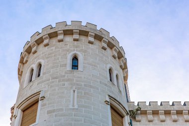 Mimari detaylarla mavi gökyüzüne karşı ortaçağ taş kulesi.