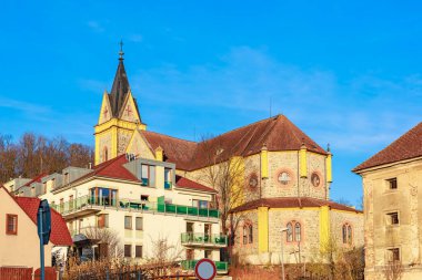 Açık mavi gökyüzüne karşı tarihi kilise ve yerleşim mimarisi.