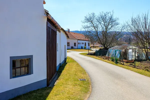 Güneşli bir günde beyaz evleri ve seraları olan kırsal bir yol..