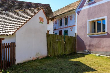 Büyüleyici renkli evleri ve ahşap çitleri olan köy manzarası. 21 Mart 2025, Holasovice, Çek.