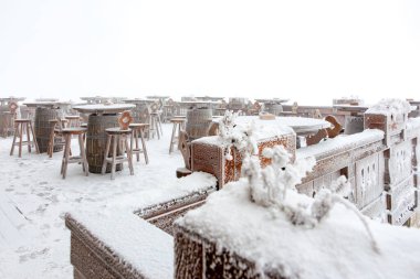 Kış manzarasında kırsal varilleri ve tabureleri olan karla kaplı bir bahçe..